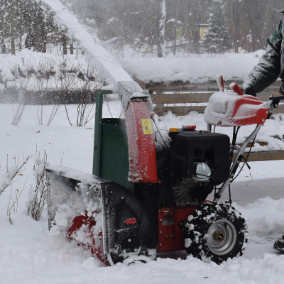 Tracteur déneigeant la route avec une balayeuse entraînée par courroie